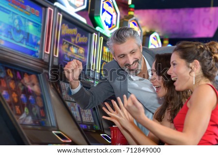 people gambling in a casino playing slot machine Royalty-Free Stock Photo #712849000