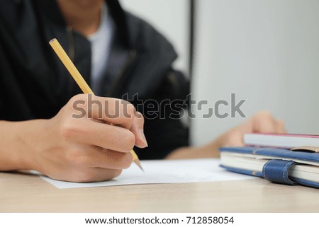 close up on student hand writing something or doing homework and examination in the classroom,diligent people concept