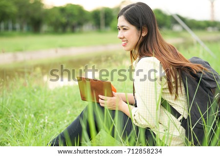 close up asian young student woman reading book alone at outdoor park at university campus with concentrate,education and people concept