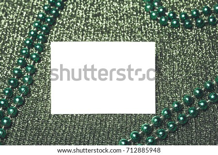 White card on lurikish green background with green mirror beads