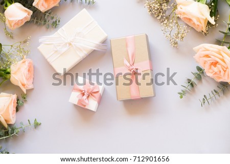 gift or present box and flowers on blue table from above