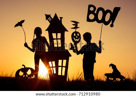 Happy brother and  sister playing outdoors at the sunset time. Kids having fun. Concept of happy Halloween party.