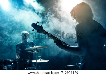 A drummer and bass guitarist. Rock concert. Scene. Smoke Stage light. Royalty-Free Stock Photo #712921120