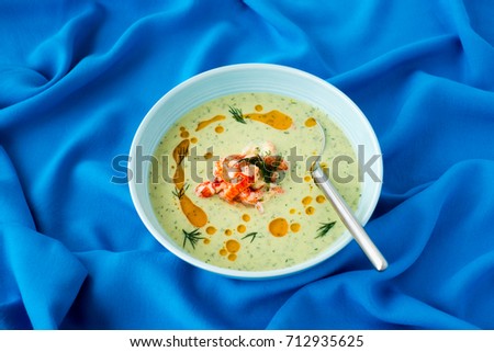 Chilled Cucumber and Crayfish Soup with dill on blue background with copy space. Selective focus and shallow depth of field.
