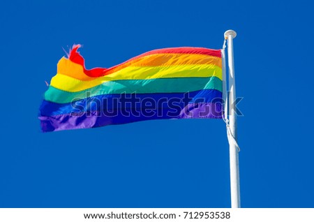 Rainbow flag isolated on blue sky background.