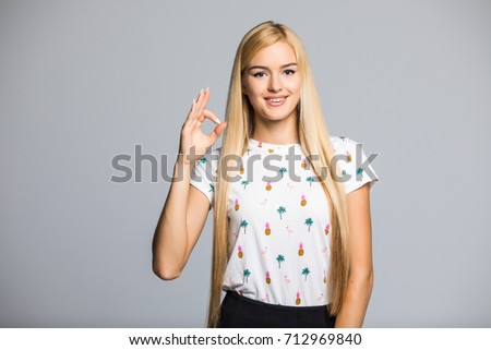 Blonde woman with okay gesture on gray background