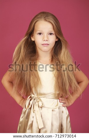 Beautiful blonde little girl in golden dress, isolated on plum background