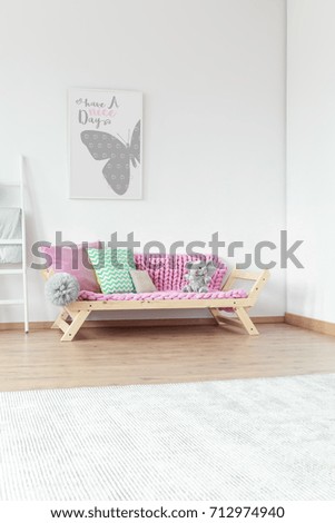 White carpet in front of sofa with mint and pink pillow and grey plush toy in pastel room