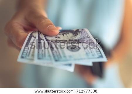 Female hands counting US Dollar bills or paying in cash . Royalty-Free Stock Photo #712977508