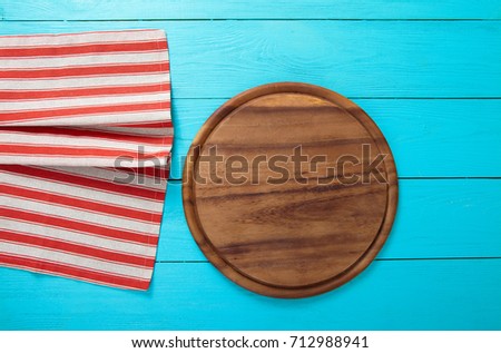 Cutting board and striped tablecloth on blue wooden table. Top view and copy space. Place for pizza