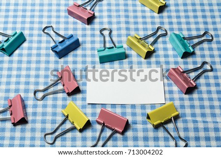 White card on a checkered background and clerical clothespins
