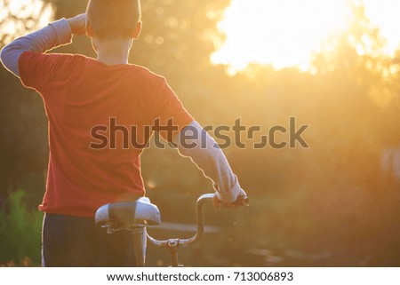 A boy with a bicycle looking forward a background of  sunrise (concept)