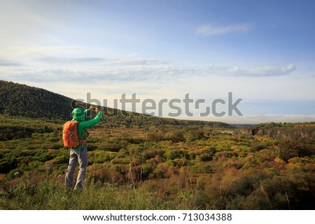 hiking woman use smartphone taking photo in the autumn forest