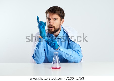 A doctor in a medical gown is sitting at a table in a hospital, with only laboratory utensils, a medical facility, healthcare                               