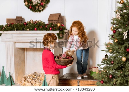 little siblings decorating christmas tree together at home