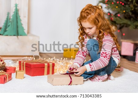 focused little girl unpacking christmas gift at home