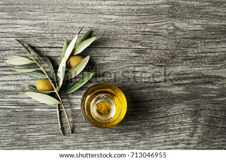 Olive oil and olive branch on wooden table