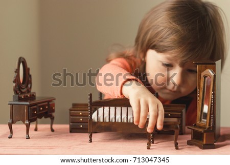 Little girl playing with doll house furniture