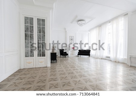 Luxury white interior of living spacious room with elegant chic black furniture and high windows.