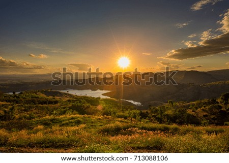 the sun is falling behind the mountain. orange light shines on the forest and dams. Is a picture of beautiful scenery