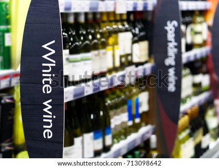 Wine shelf aisle in supermarket with White Wine ad on display in foreground 