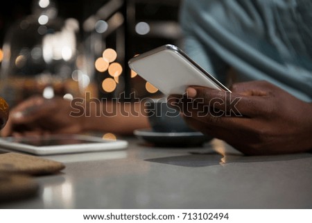 Mid section of man using mobile phone in restaurant