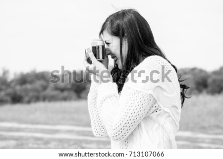 A young amateur photographer with an old camera in the field takes pictures of the neighborhood. Girl with a photo camera on the nature have a good mood on a vacation