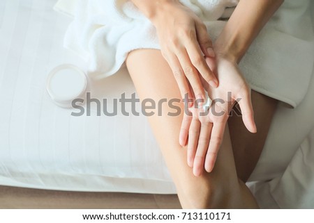 Asia woman sitting on bed and applying cream on Hand. Royalty-Free Stock Photo #713110171