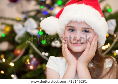 Smiling little girl in Santa hat on Christmas. Happy Christmas time