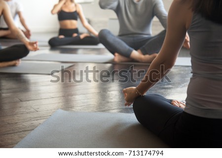Young sporty people practicing yoga lesson with instructor, sitting, making Alternate Nostril Breathing, nadi shodhana pranayama exercise, working out, close up image. Wellbeing and wellness concept  Royalty-Free Stock Photo #713174794