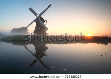charming windmill by lake at  misty sunrise
