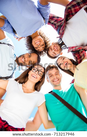Low angle shot of six international students with toothy smiles, posing and bonding, on a sky background. Cheerful, smart and successful teens