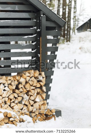 Stack of firewood near the wall of a wooden building in winter time


