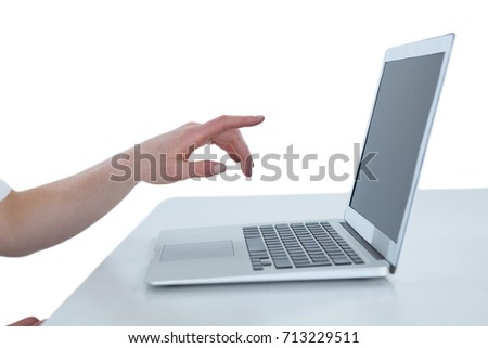 Cropped image of businesswoman gesturing on laptop computer at table against white background