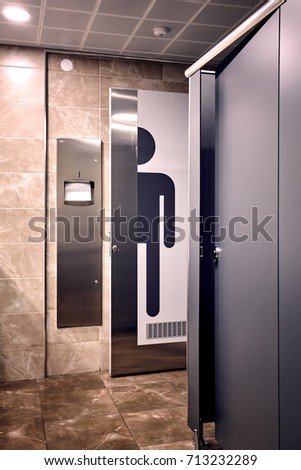 An interior shot of a men's room wc. A big man sign on the toilette door next to the towel rack. 