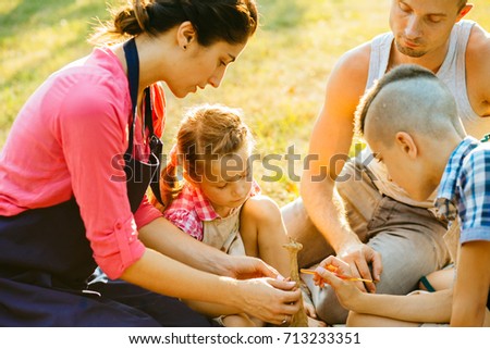 Happy mother, father and two kids are painting in the park. The concept of a happy family.