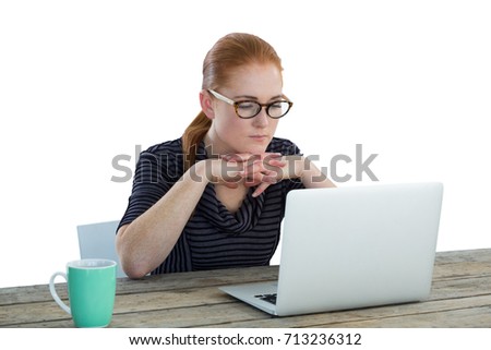 Businesswoman looking at laptop while sitting against white background