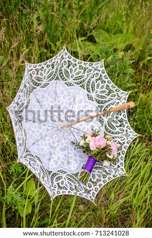 Beautiful bouquet of beige roses and pink peonies on an inverted openwork white wedding umbrella in green grass