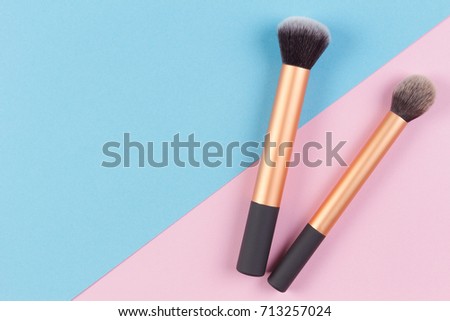 Make up brushes on pink and blue background. Top view.