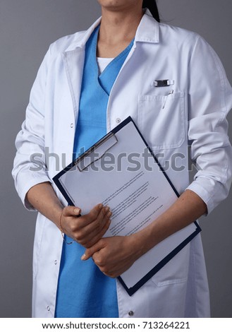 Female doctor standing with a folder and medical stethoscope , isolated on gray background
