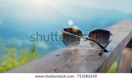 Sunglasses lying on the board against the background of the landscape with the mountains.