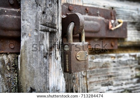 Close up of rusty padlock on old wooden door.