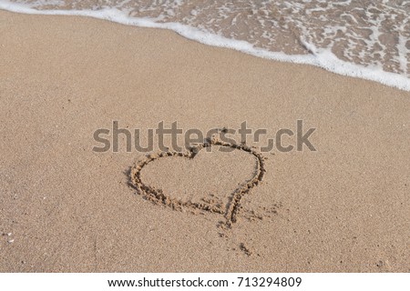 Heart symbol in the sand by the ocean 