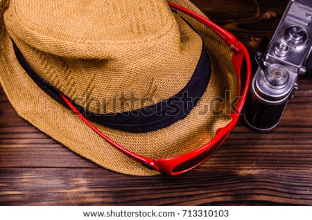 Old rangefinder camera, sunglasses and hat on wooden table