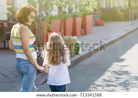 Urban portrait of mother and daughter. Back view.