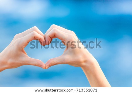 Hand shaped heart against a blue sea background. Love people concept. 