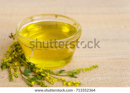 Fresh honey in glass jar on wooden background with wild yellow clover, sweet clover.