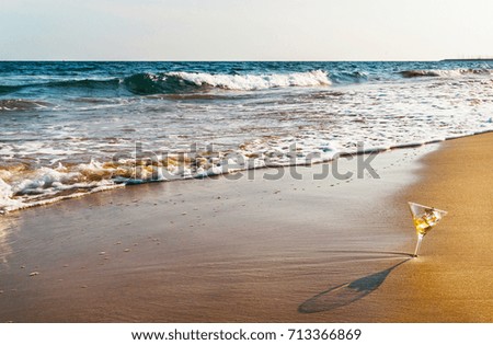 drink in a martini glass on the background of the waves affecting the sandy beach, relax on the beach, refreshing drink during the holidays, summer time