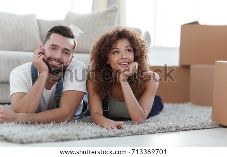 Young couple lying on the rug on the background of a new apartment