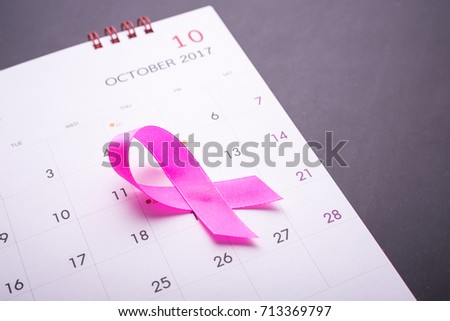 Breast Cancer concept : Pink ribbon symbol of breast cancer and calendar on black stone board background
